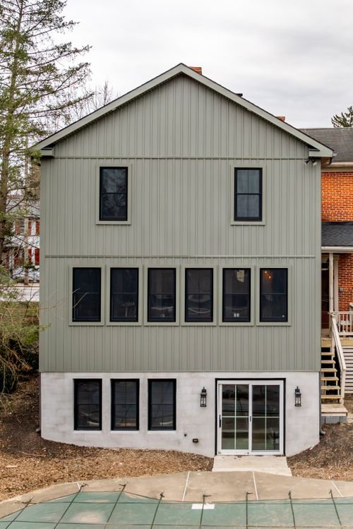 Gray home addition with black-framed windows, French doors and a chimney against the sky