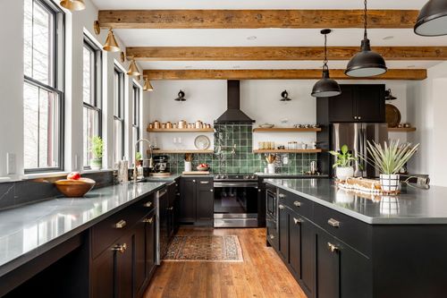 Black kitchen with gray quartz counters, fresh herbs and exposed wood ceiling beams