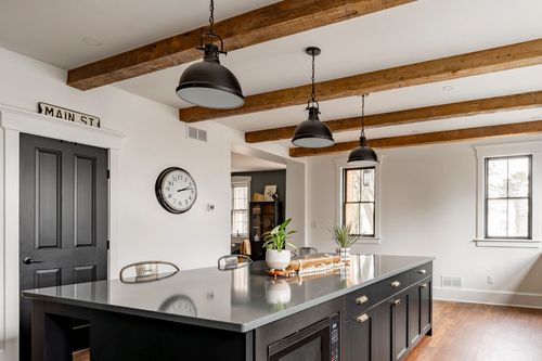 Kitchen island with black cabinetry, a vintage MAIN ST sign and wall clock by a black door