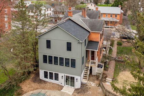 Aerial view of a gray board-and-batten addition attached to a red-brick historic home