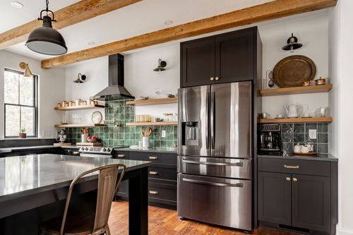 Kitchen with stainless refrigerator, green tile backsplash and open wood shelving