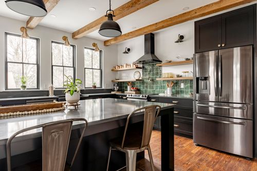 Kitchen island with metal barstools, stainless refrigerator and wood beam ceiling