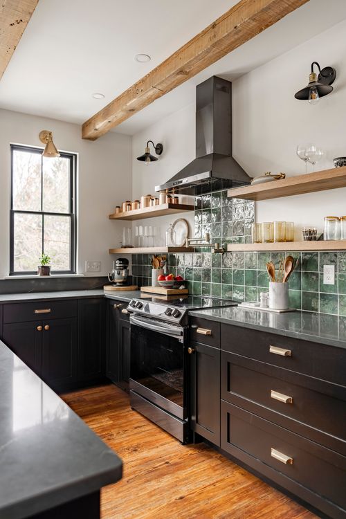 Kitchen with black range, green tile backsplash, brass hardware and open wood shelving