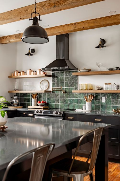 Kitchen with green tile backsplash, black range and gray soapstone island under a black pendant