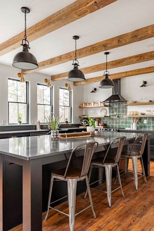 Kitchen island with metal barstools, exposed wood beams and rows of windows