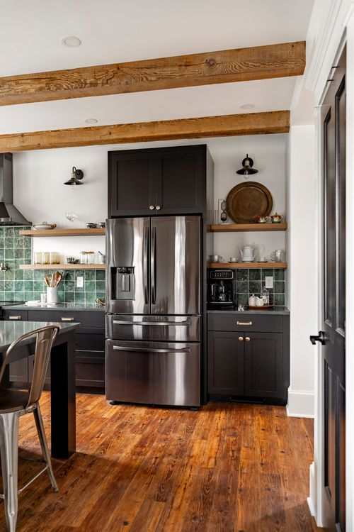 Stainless refrigerator with green tile backsplash under a reclaimed wood beam ceiling