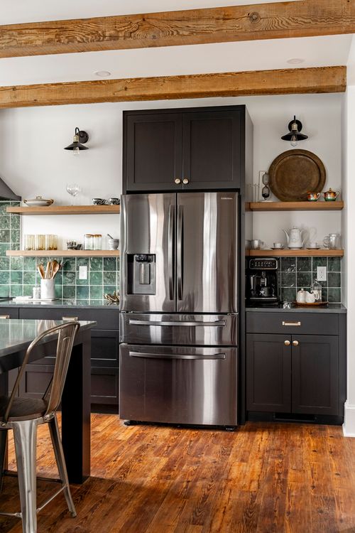 Stainless refrigerator flanked by open wood shelving and a built-in coffee station