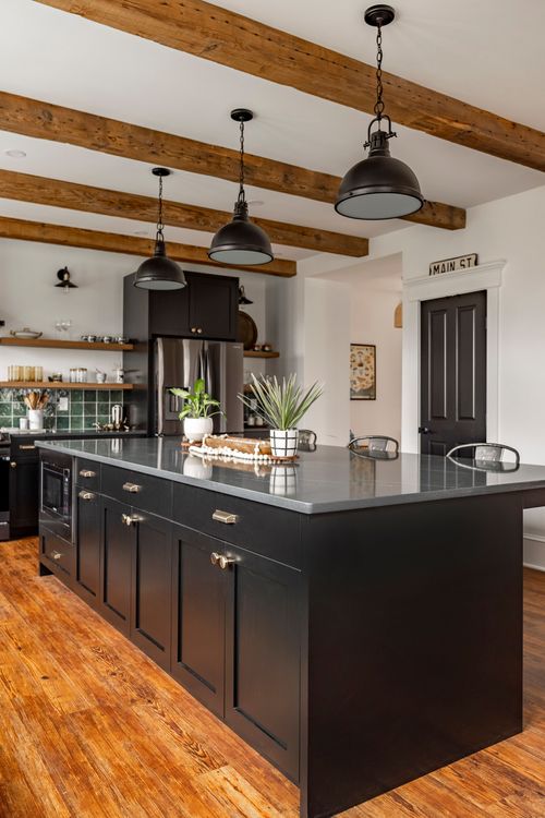 Black kitchen island with pendant lighting and a MAIN ST sign above a black door