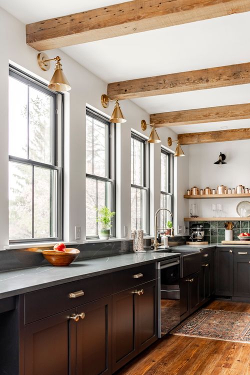 Kitchen counter along a row of windows with brass sconces and a soapstone countertop