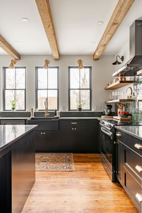 Kitchen with black farmhouse sink, black range, wood beams and a vintage runner rug