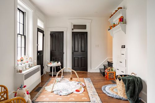 Mudroom with black paneled doors, a radiator and a colorful children's play mat