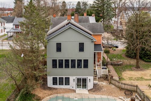 Aerial view of a gray home addition with French doors, wood deck stairs and a red-brick neighbor