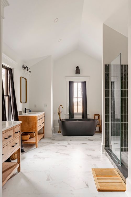 Vaulted bathroom with wood vanity, black soaking tub and dark tiled shower