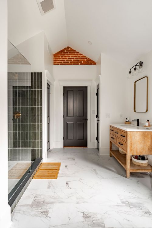 Bathroom with an exposed brick gable accent, black door and dark tiled shower