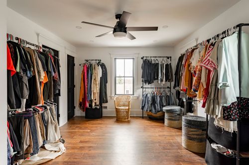 Walk-in closet with open clothing racks, storage baskets and a ceiling fan