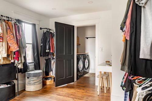 Walk-in closet with a black door open to a laundry room with washer and dryer