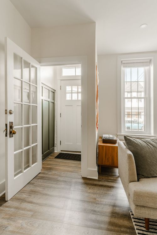Entryway with a glass-paned front door, mid-century console table and wood plank flooring