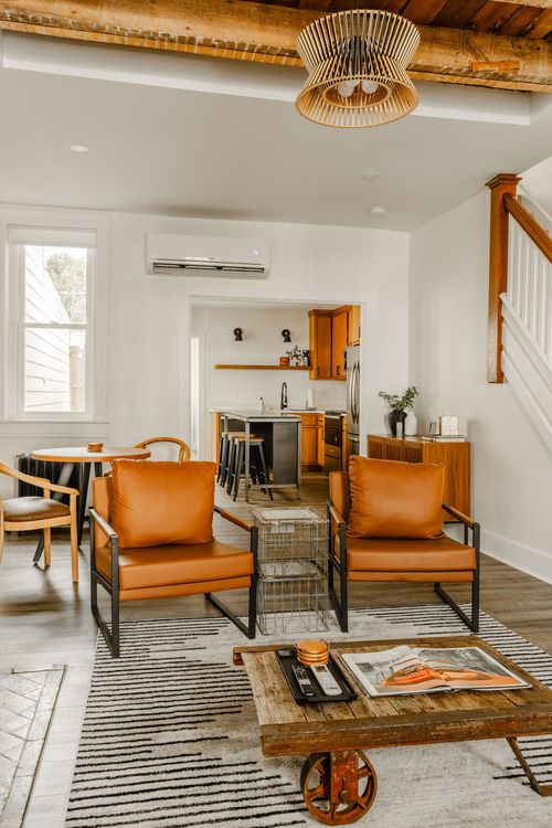 Living room with leather chairs, a rustic coffee table and kitchen visible through the doorway