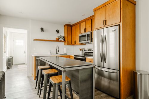 Kitchen with wood cabinetry, stainless appliances and a view down the hallway to the back door