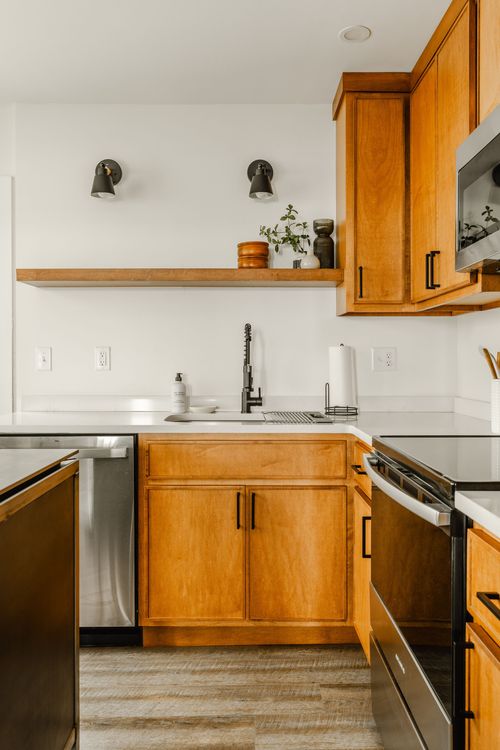 Kitchen sink and dishwasher nook with wood cabinets and a matte-black faucet