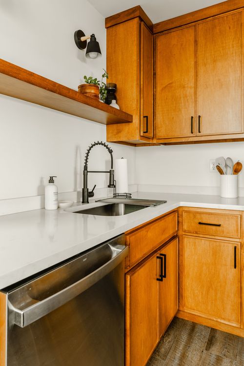 Kitchen sink with black faucet, stainless dishwasher and wood cabinetry