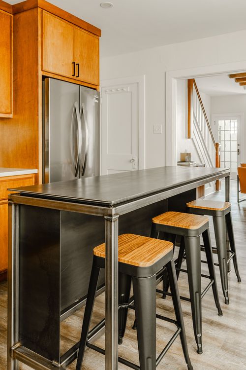 Kitchen with a metal-topped island, wood barstools and a stainless refrigerator