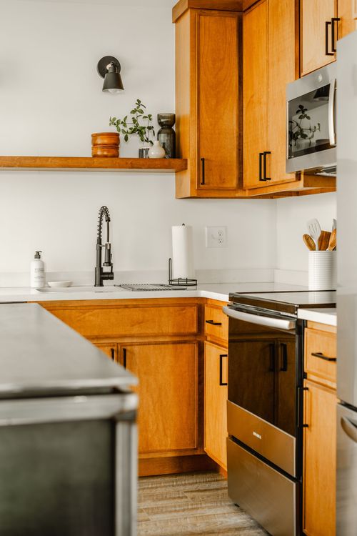 Kitchen counter with black faucet, wood cabinets and stainless range beyond