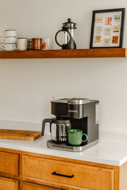 Coffee bar with open wood shelving, mugs, French press and framed artwork
