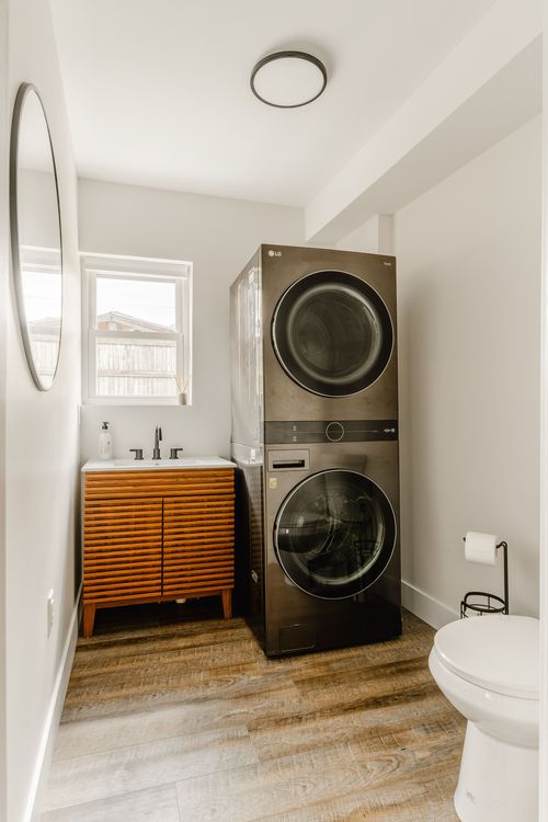 Bathroom laundry nook with a stacked black washer-dryer, fluted vanity and toilet