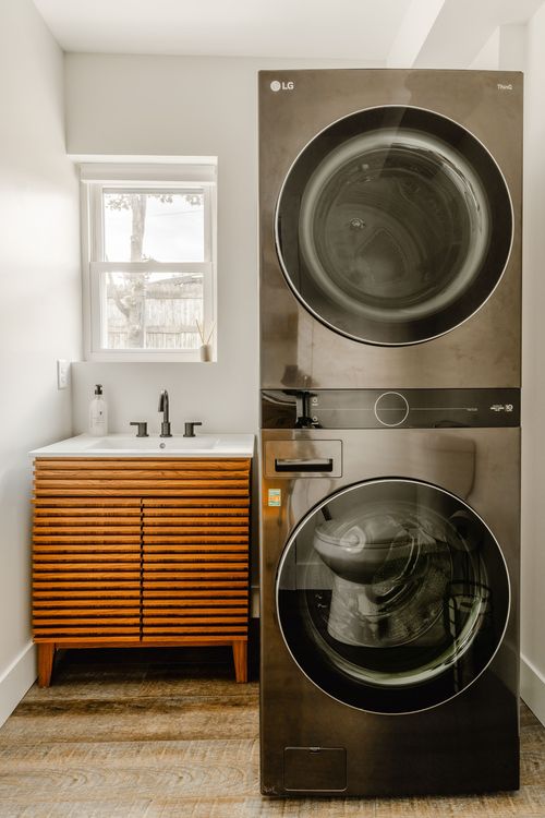 Laundry nook with a stacked black LG washer-dryer beside a fluted wood vanity