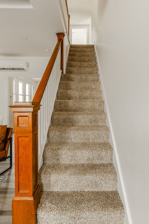 Carpeted staircase with a wood newel post and white balusters