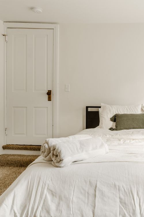Bedroom detail with rolled white towels on the bed and a white paneled door