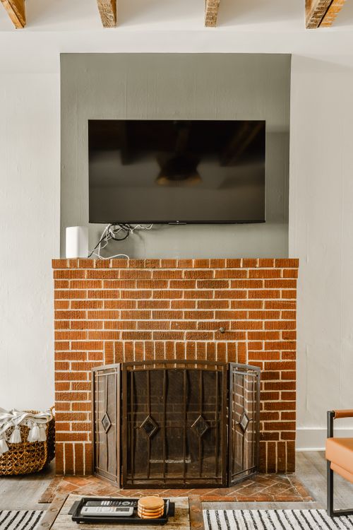 Brick fireplace with a mounted flat-screen TV and iron fireplace screen