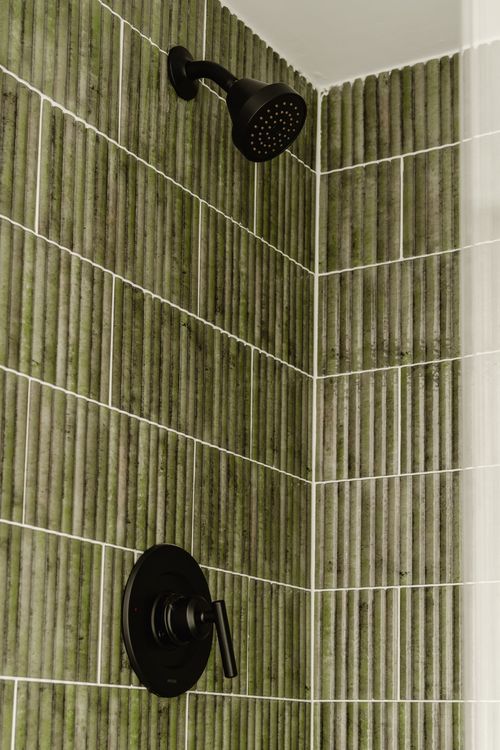 Close view of green ribbed tile shower wall with matte-black fixtures