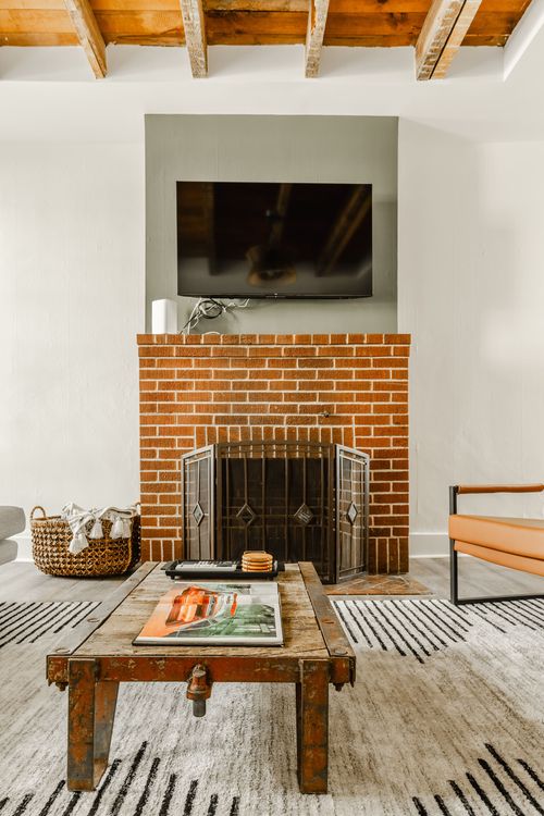 Brick fireplace with mounted TV, reclaimed wood coffee table and a striped area rug