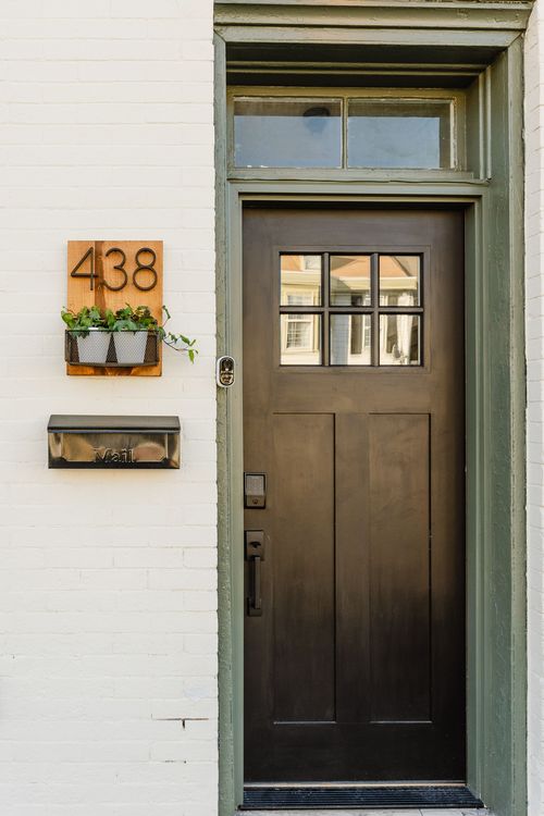 Black front door with glass panes, a wood house-number sign and a black mailbox