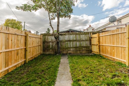 Wood privacy fence enclosing a small backyard with a concrete path and a tree
