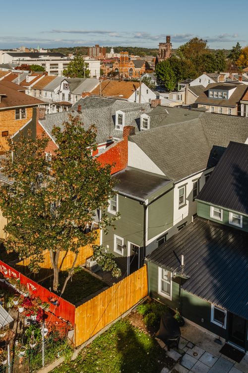 Aerial view of rooftops and colorful rowhomes with autumn trees in a small town
