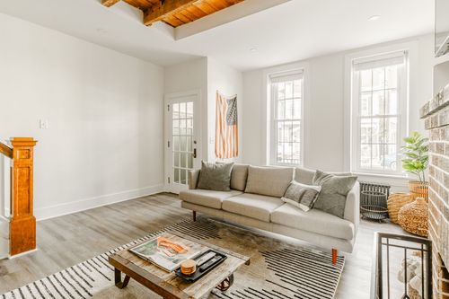 Living room with a striped flag wall hanging, linen sofa and brick fireplace corner
