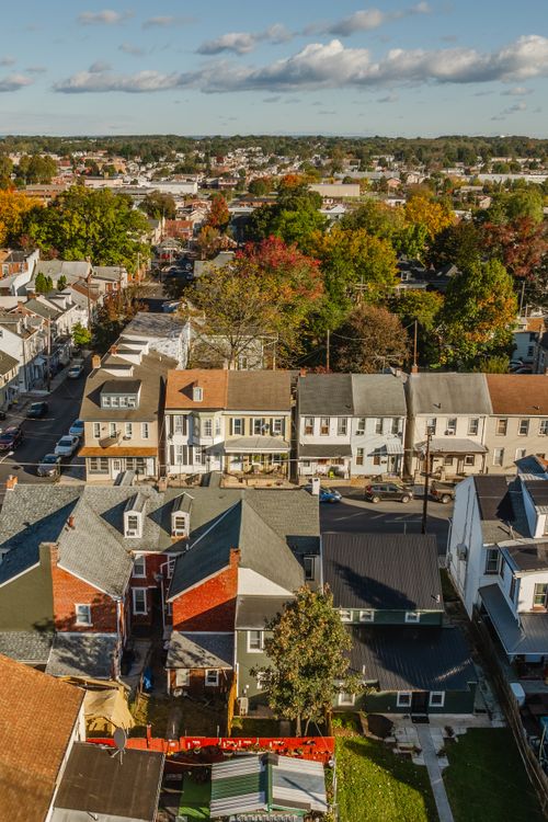 Aerial view of a town street lined with rowhomes and trees in fall color