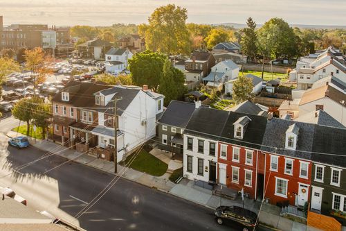 Aerial dusk view of a rowhome-lined street with rooftops and trees