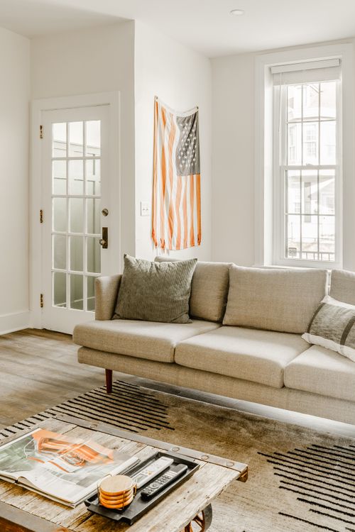 Living room with a linen sofa, striped flag art and a glass-paned door