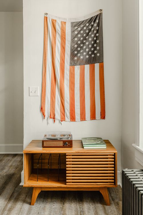Mid-century record cabinet with a turntable beneath a striped flag wall hanging