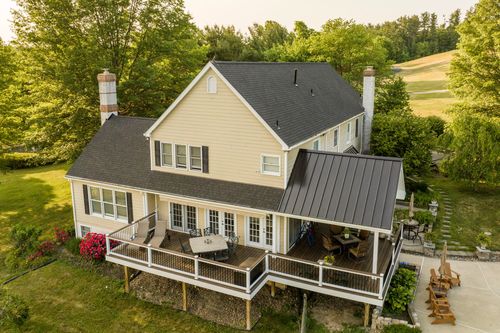 Aerial view of a farmhouse covered porch with dining furniture and French doors