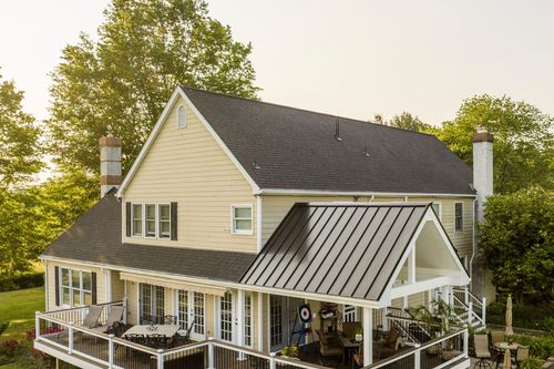 Aerial view of a farmhouse deck with a dining table and gabled standing-seam porch roof