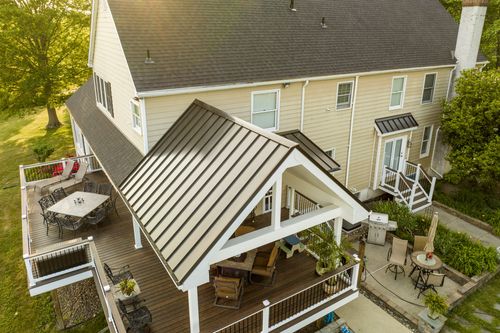 Aerial view of a farmhouse deck with an outdoor dining set, grill and covered porch