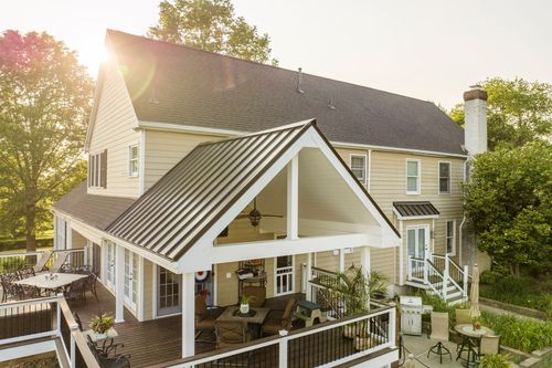 Aerial sunlit view of a covered porch with a ceiling fan, seating and wood deck