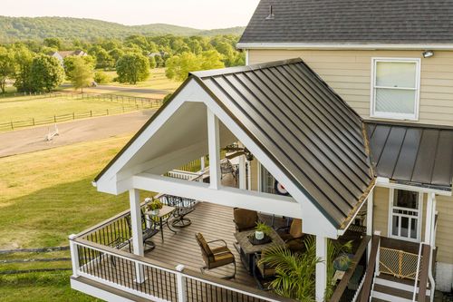 Aerial view of a covered deck overlooking rolling hills and a horse pasture