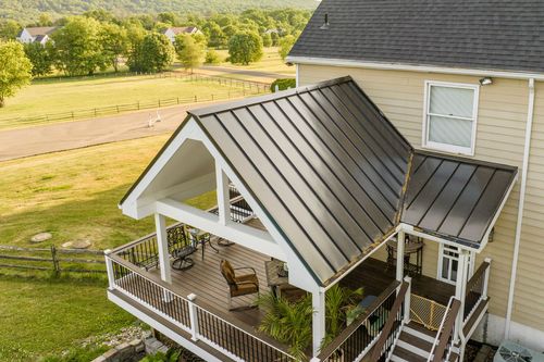 Aerial view of a farmhouse covered deck with lounge seating overlooking pastureland