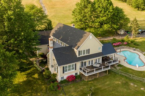 Aerial view of a farmhouse chimney, stone facade and pool in evening light